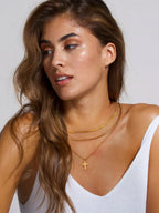 18K gold-plated three-layered cross necklace shown on a display, featuring intricate cross pendants and layered chain design.