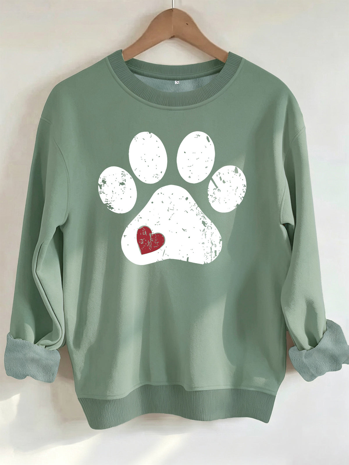 Sage green crewneck sweatshirt with a distressed white paw print and small red heart detail.