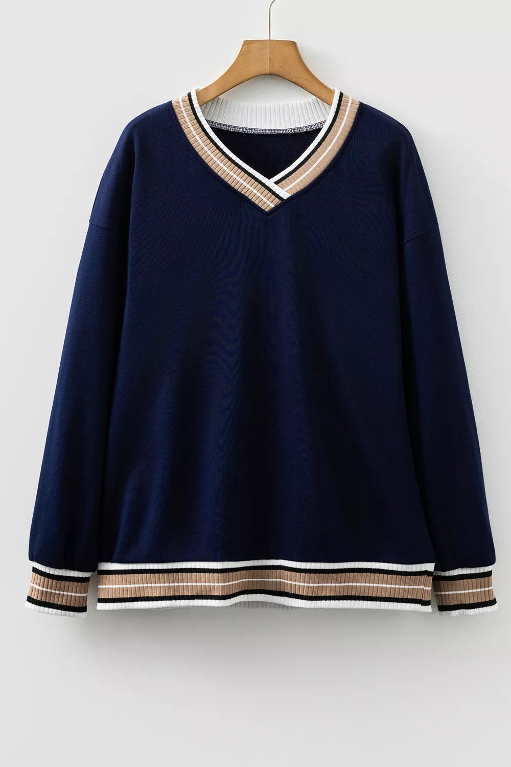 Contrast striped trim V-neck sweatshirt from Trendsi featuring a casual fit and ribbed cuffs, displayed on a hanger.
