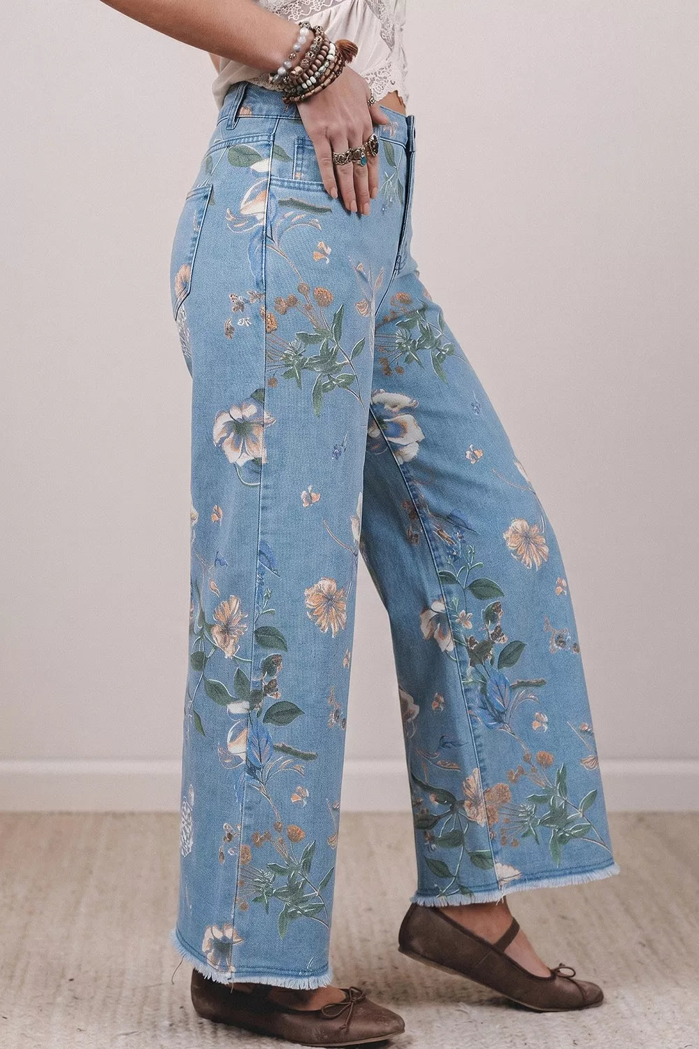 Floral print wide-leg jeans from Trendsi featuring a relaxed fit and vibrant floral pattern, shown on a model.