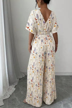Floral print wide-leg pleated jumpsuit from Trendsi, featuring a stylish design with flowing fabric and vibrant flower patterns.