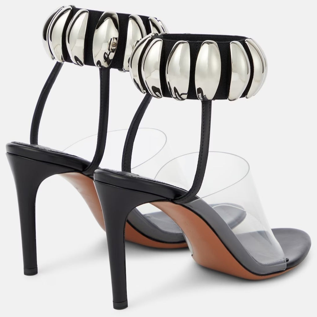 Clear PVC open-toe stilettos with black heels, insoles, and metallic silver bead-embellished ankle cuffs.