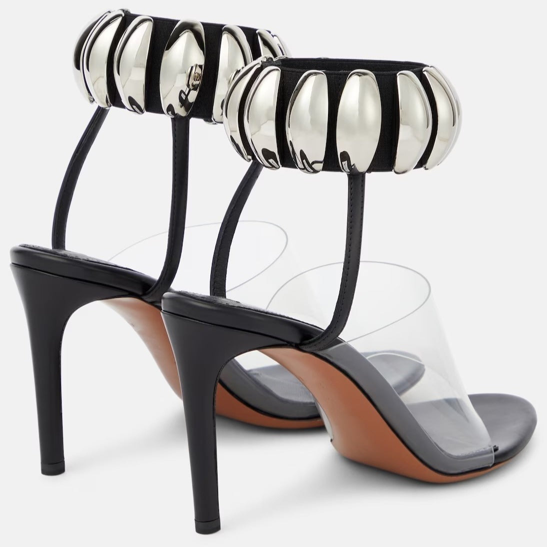 Clear PVC open-toe stilettos with black heels, insoles, and metallic silver bead-embellished ankle cuffs.
