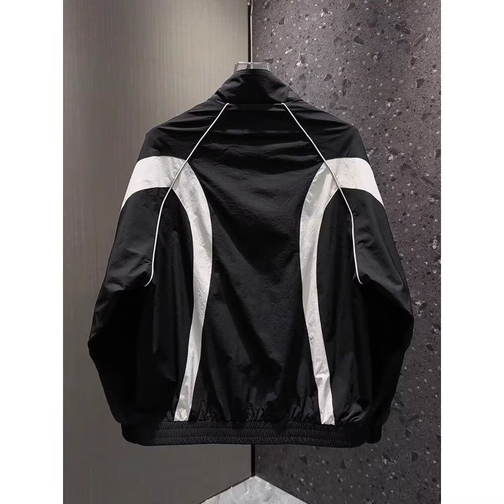Back view of a black nylon athletic jacket featuring white piping, curved white panels, and a high collar.