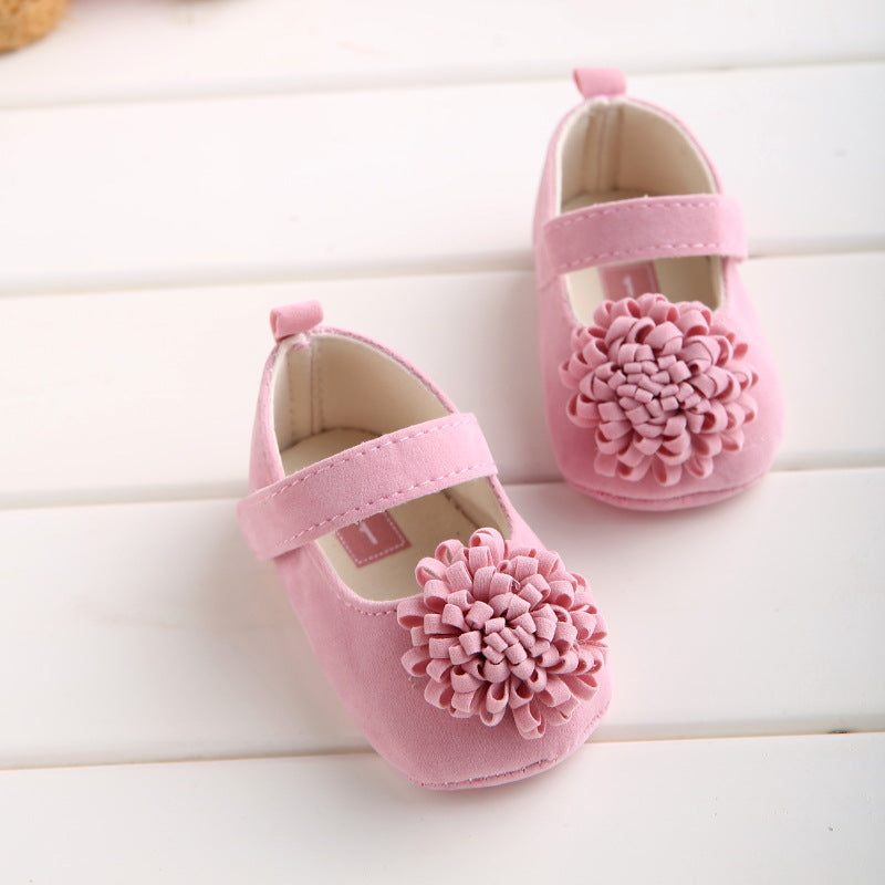 Pink suede baby shoes with velcro strap and large fabric flower accent on toe.