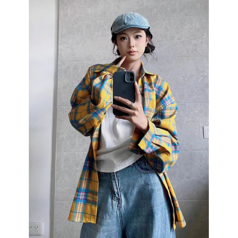 A person wears an oversized yellow and blue plaid cotton flannel shirt, white top, and jeans.