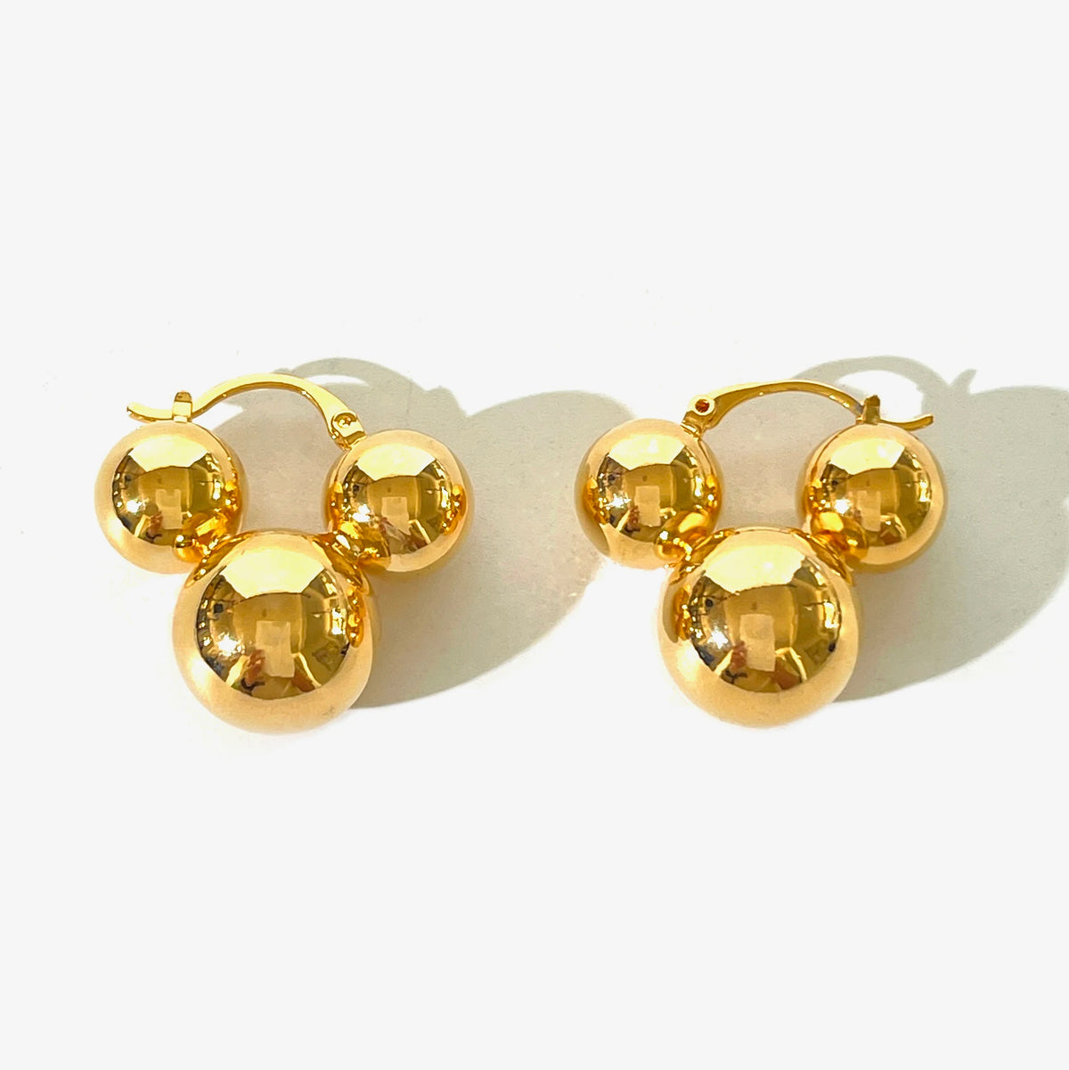 Gold metal hoop earrings featuring three spherical beads arranged in a Mickey Mouse shape.