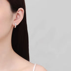Sterling silver moissanite huggie earrings with sparkling gemstones, showcasing a sleek and elegant jewelry design.