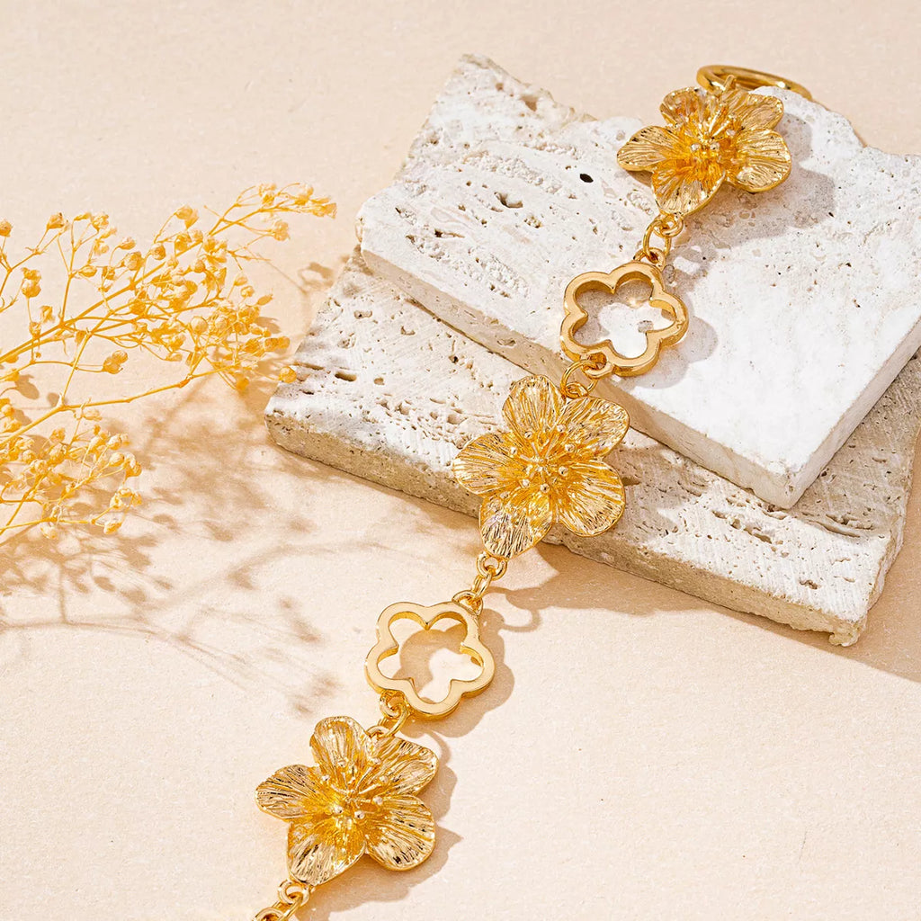 Gold-plated flower bracelet with delicate floral design, showcasing intricate metalwork and shimmering finish.