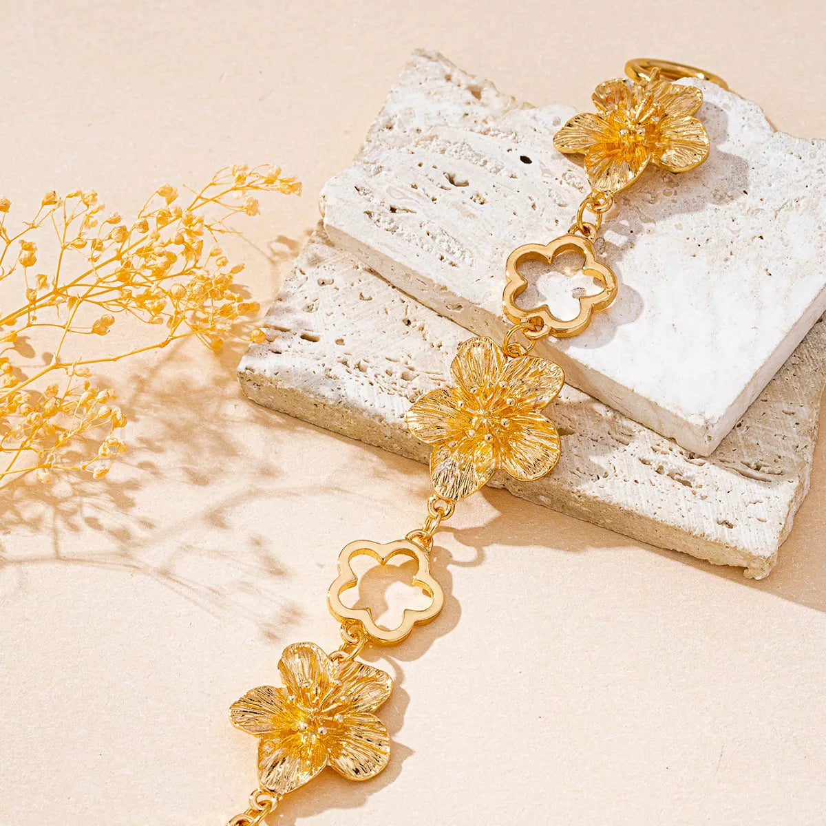 Gold-plated flower bracelet with delicate floral design, showcasing intricate metalwork and shimmering finish.