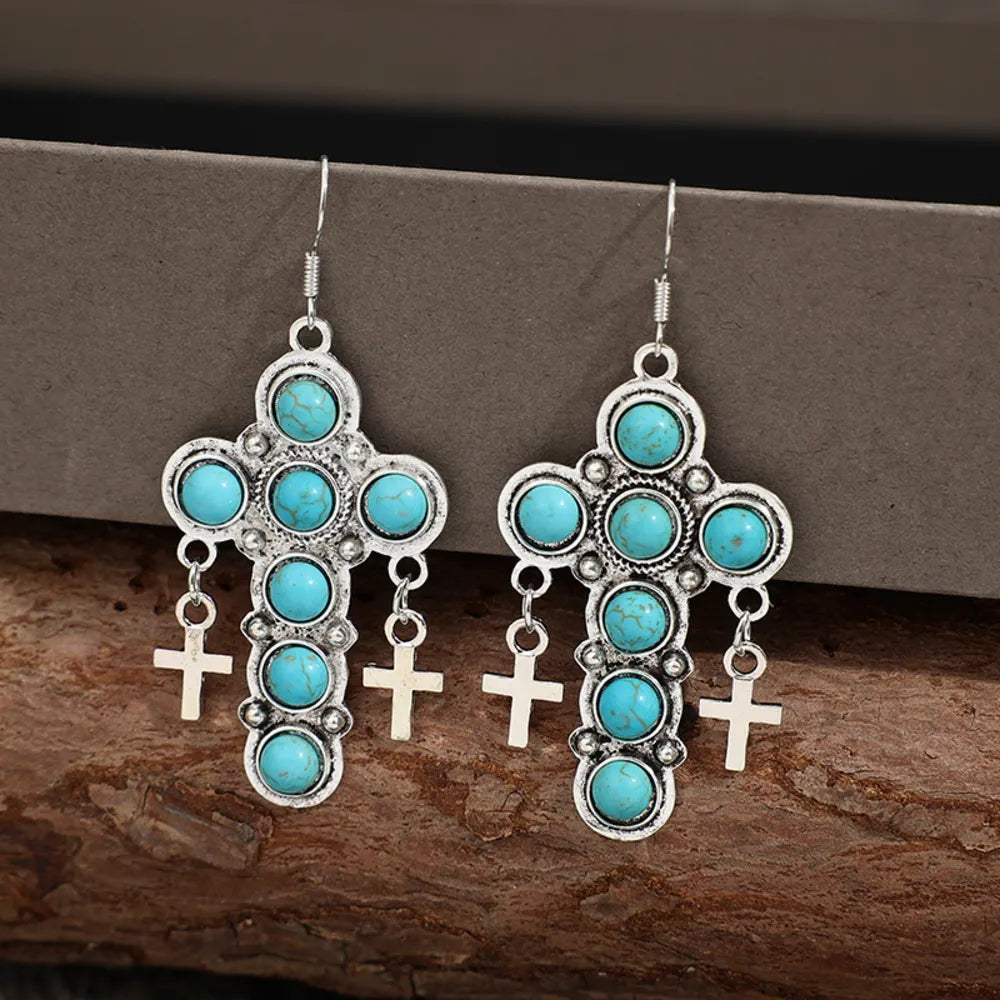 Turquoise cross-shaped earrings from Plush Fashion Hub, featuring vibrant artificial turquoise and silver-tone metal details.