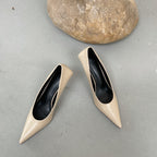Beige faux leather pointed-toe stiletto pumps with a smooth finish and black inner lining.