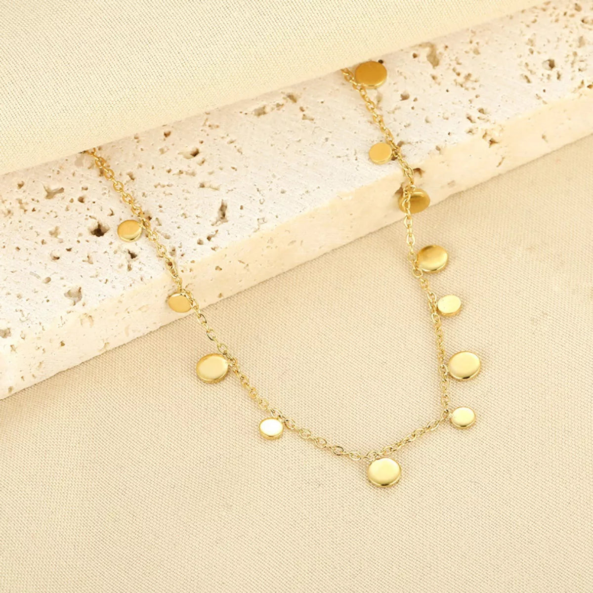 18K gold-plated charm bracelet with delicate charms and intricate details, styled on a neutral background.