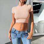 Women's slim fit midriff-baring short sleeve crop top by FitiqueFit, casualwear, shown on a model, light color with a round neckline.