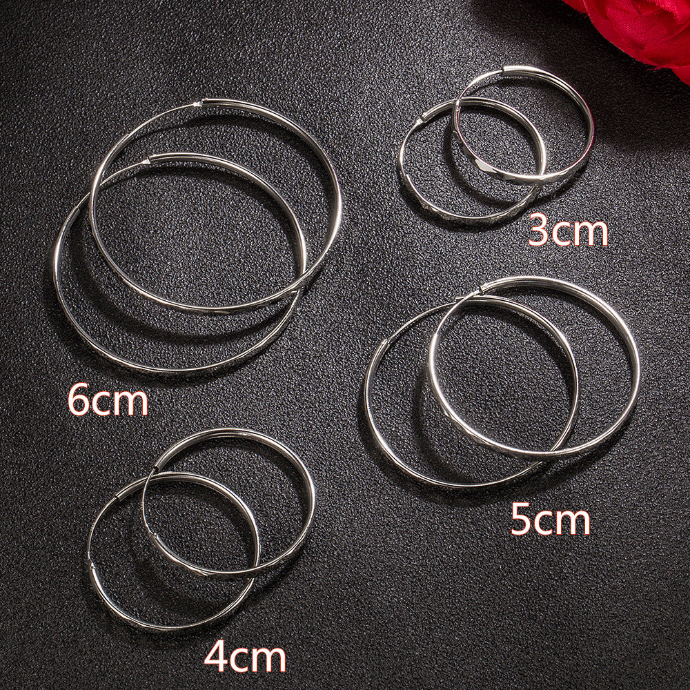 Silver hoop earrings in four sizes: 3cm, 4cm, 5cm, and 6cm, laid flat on a textured black surface.