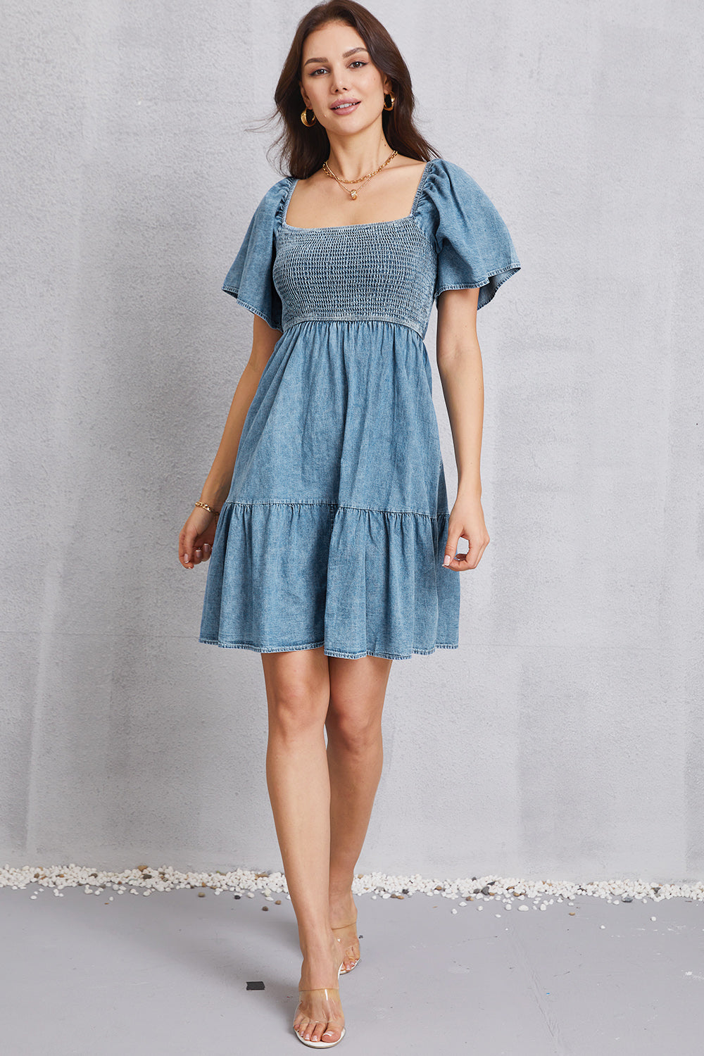 VYSN smocked square neck mini denim dress displayed on a hanger, showcasing its stylish design and fitted bodice.