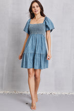 VYSN smocked square neck mini denim dress displayed on a hanger, showcasing its stylish design and fitted bodice.