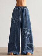 Shopimist floral appliques wide leg jeans with decorative floral patches, relaxed fit, and stylish design on light denim fabric.
