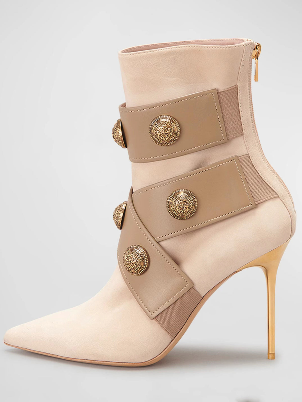 Beige suede stiletto boot with leather straps, gold lion buttons, pointed toe, and gold heel.