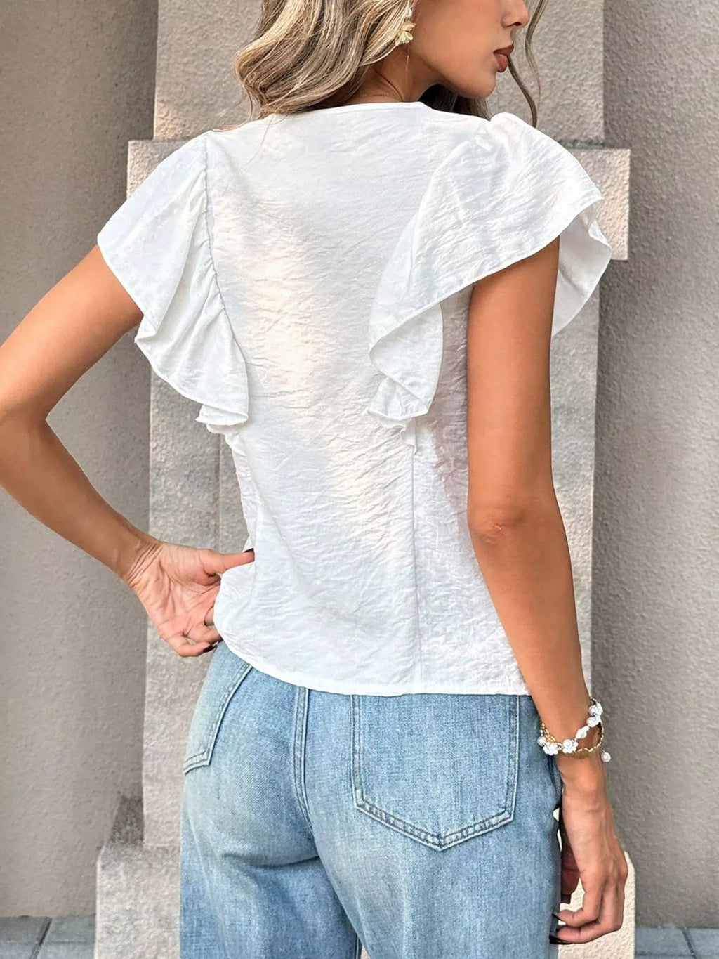 Ruffled V-neck blouse by Shopimist featuring soft fabric and feminine ruffle details, shown on a neutral background.