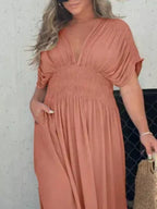 Plus size maxi dress with slit V-neck and smocked waist, trendy full-length dress from Trendsi featuring a flowing silhouette.