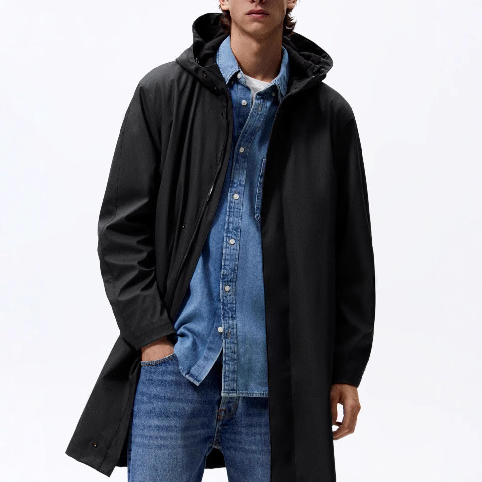 A man wearing a smooth black hooded raincoat over a blue denim shirt and jeans.