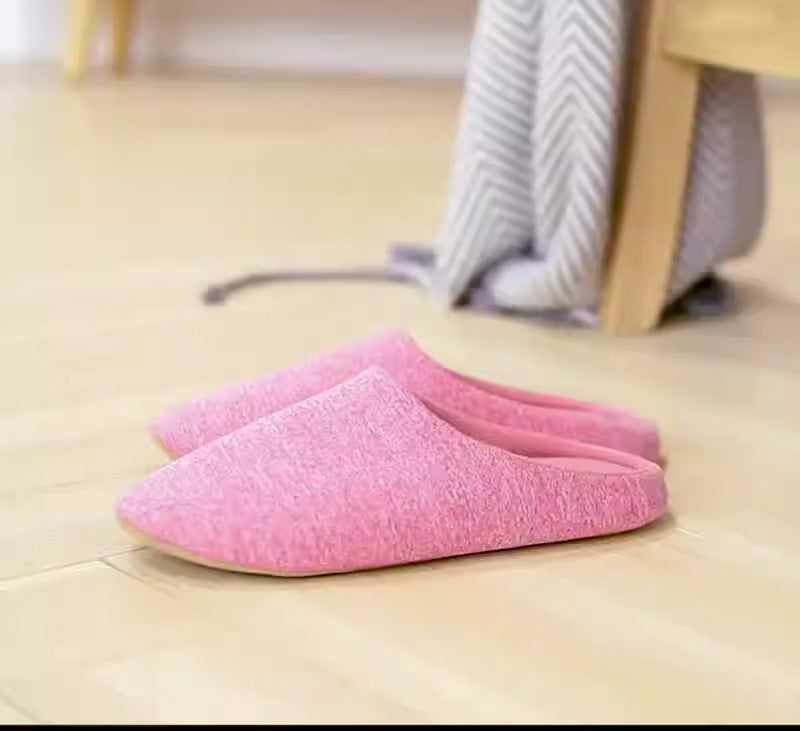 Pair of pink minimalist soft cotton indoor slippers on a light wooden floor.