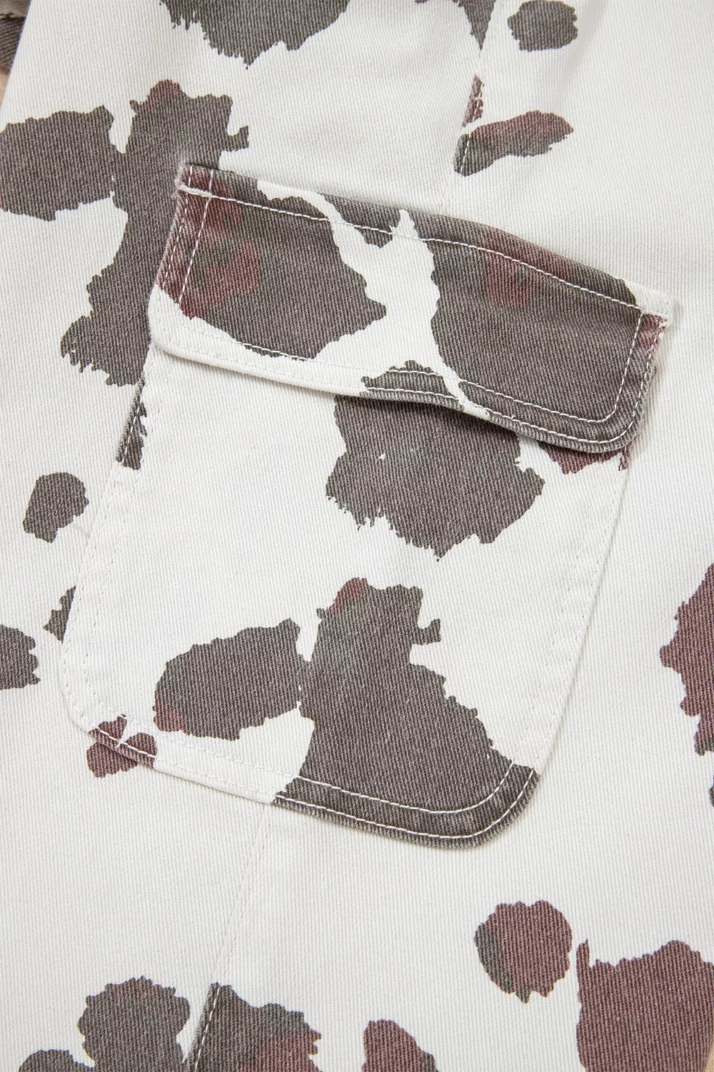 Cow spots printed multi-pocketed jeans by Plush Fashion Hub featuring black and white cow print pattern and multiple functional pockets.