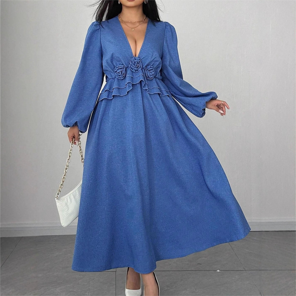 Blue denim midi dress with a V-neck, long sleeves, 3D floral accents, and a ruffled waist.