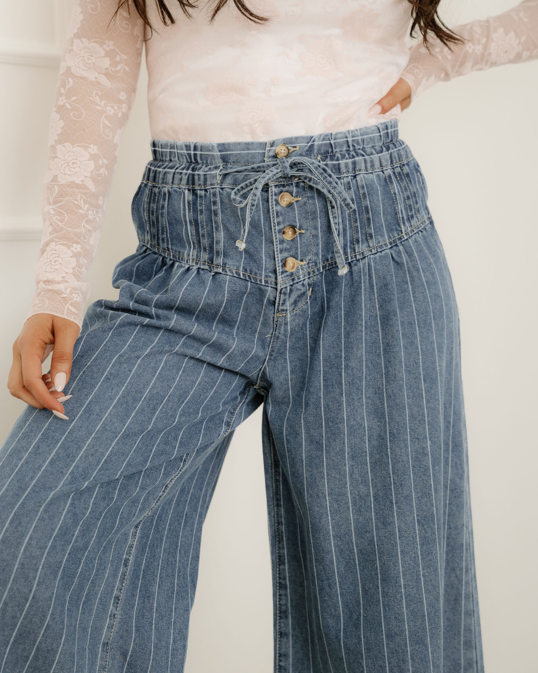 Blue striped wide-leg denim jeans with a high pleated, drawstring waistband and front buttons.