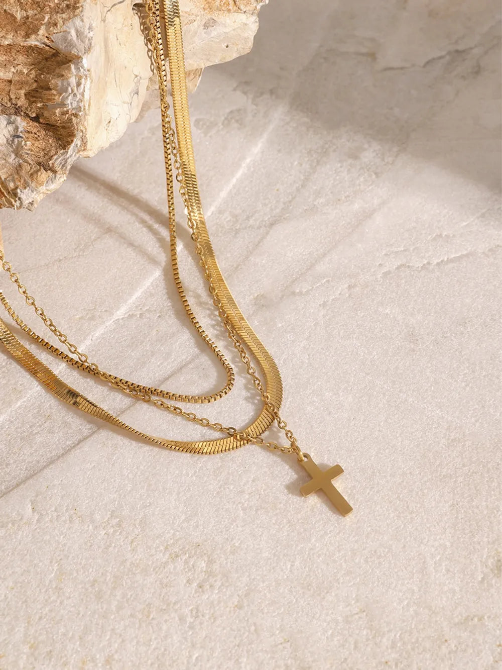 18K gold-plated three-layered cross necklace with intricate design, displayed on a plain background, showcasing its layered pendant details.