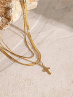 18K gold-plated three-layered cross necklace with intricate design, displayed on a plain background, showcasing its layered pendant details.