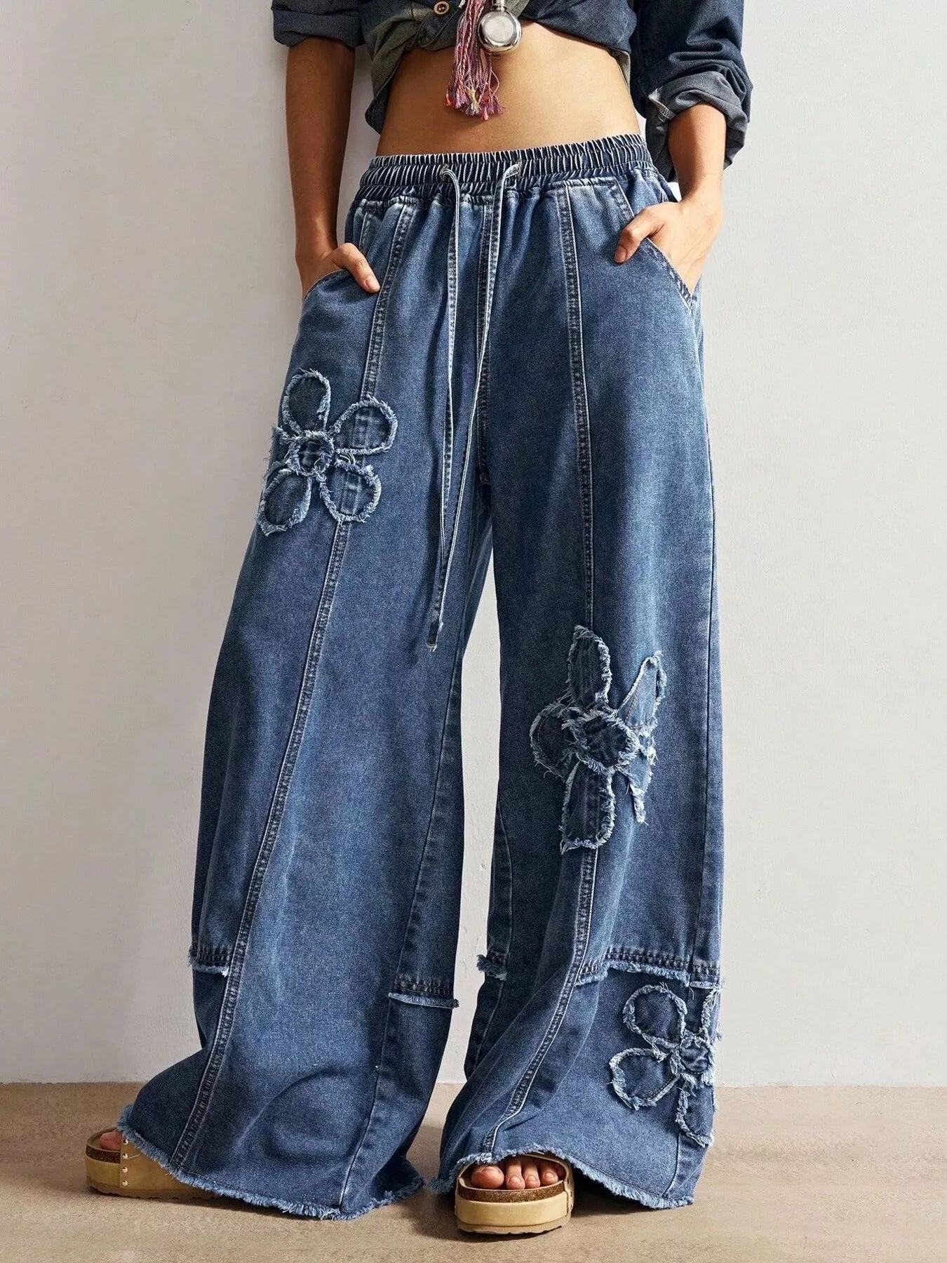 Wide leg jeans with floral appliques from Shopimist featuring colorful embroidered floral designs on denim.