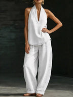 Plus size women's halter neck top and wide-leg pants two-piece dress set by Trendsi, featuring a stylish halter top and flowing wide-leg pants.