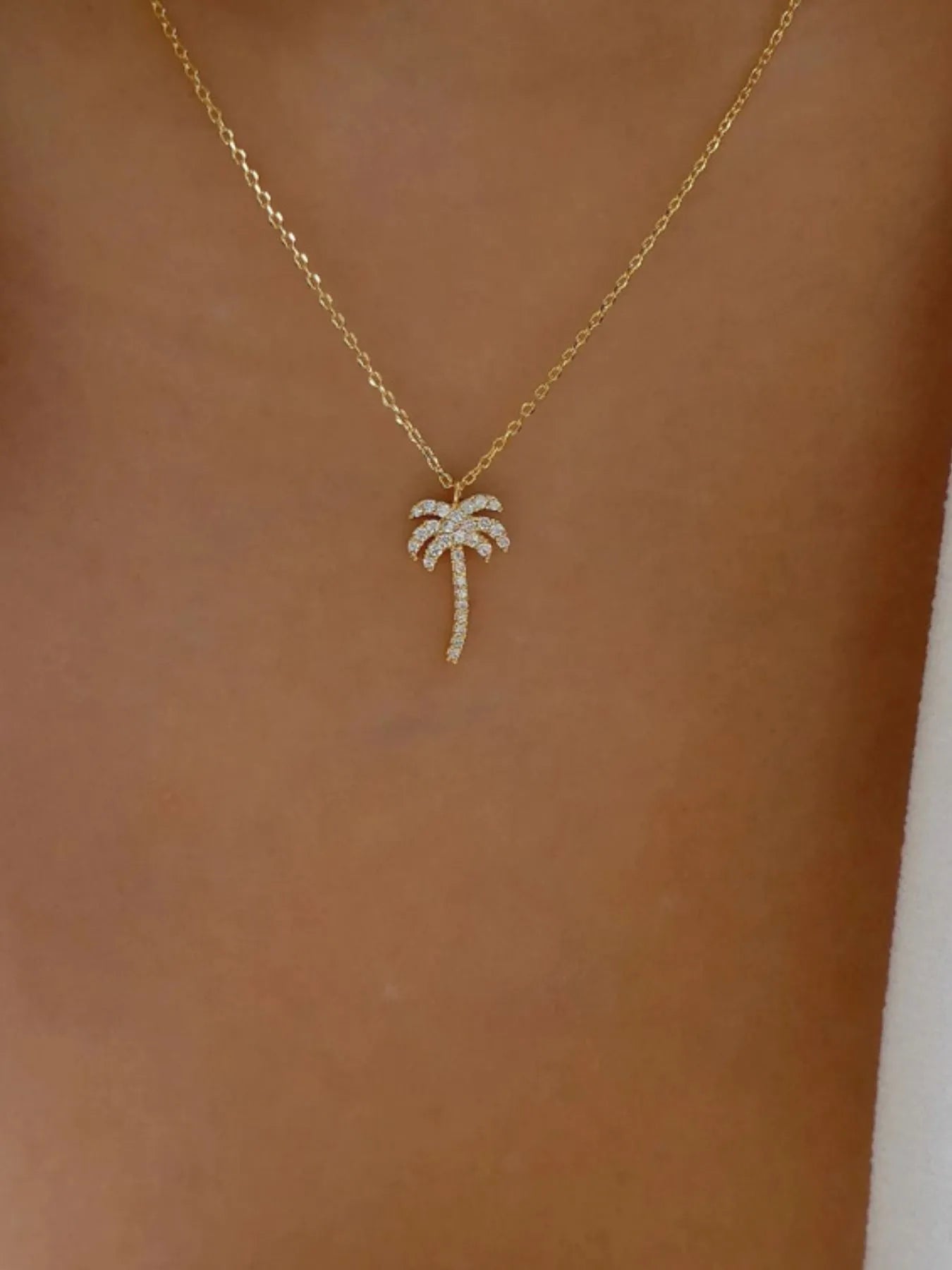 Zircon palm tree pendant necklace with sparkling stones, silver-tone chain, and detailed tropical leaf design by Plush Fashion Hub.