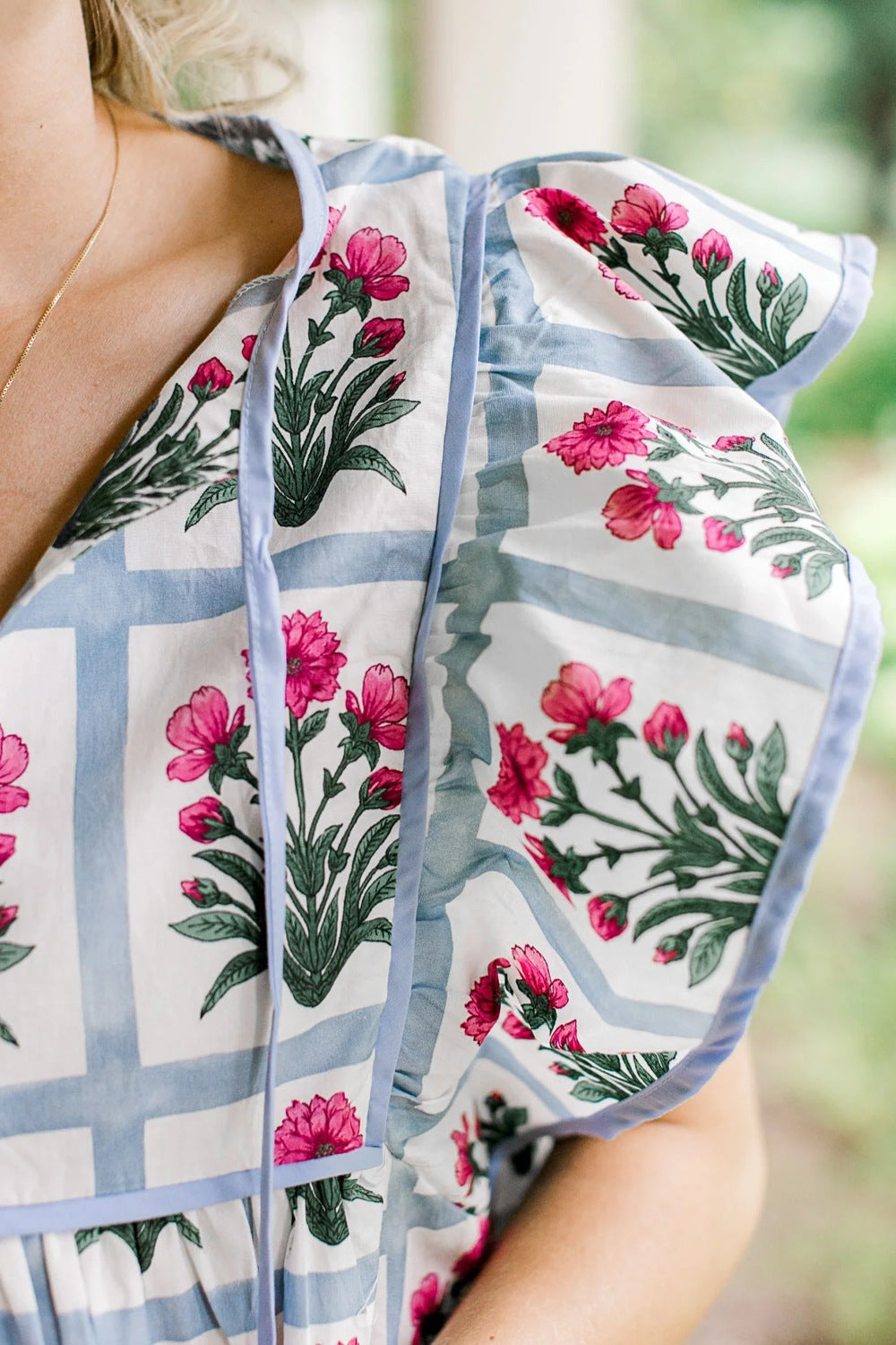 Women's floral print ruffle sleeve blouse with lightweight fabric and tied neckline, styled for a casual or dressy look.