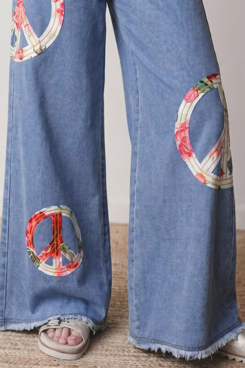 Floral Peace Sign wide leg jeans by Plush Fashion Hub featuring embroidered peace sign and floral patterns on denim.