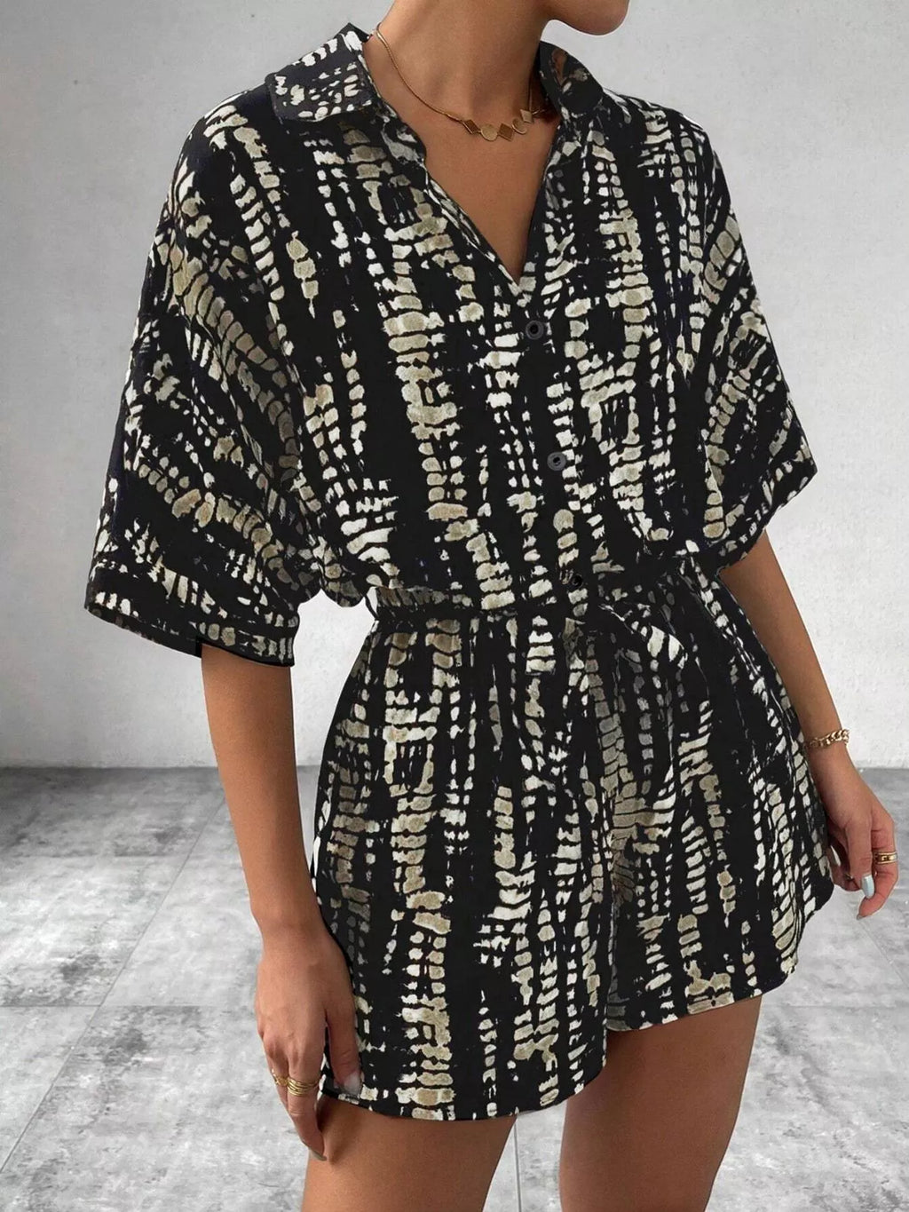 Striped button-up belted romper jumpsuit by Trendsi, featuring a stylish design with a collar, short sleeves, and a waist belt.