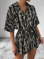 Striped button-up belted romper jumpsuit by Trendsi, featuring a stylish design with a collar, short sleeves, and a waist belt.