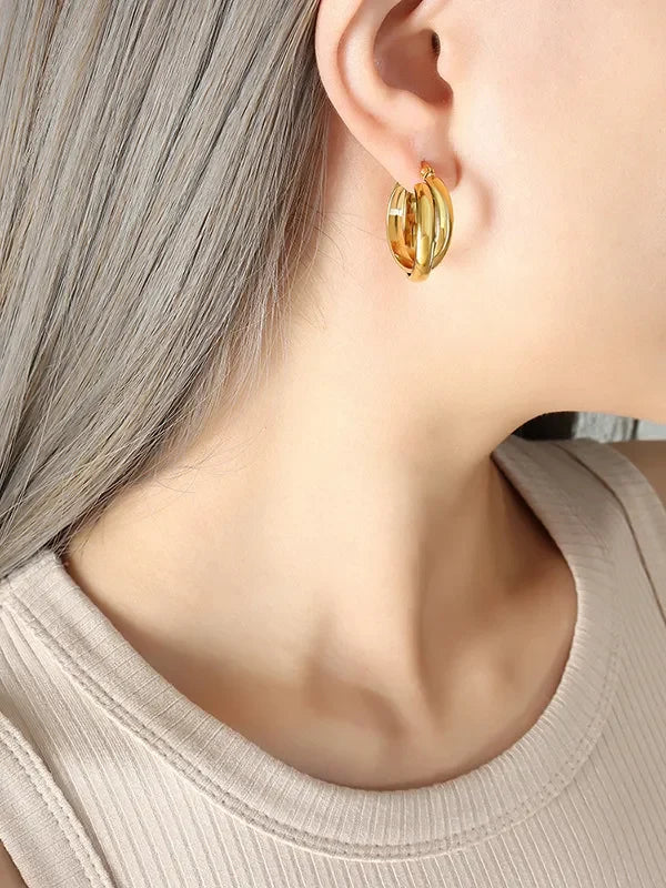 Gold-plated titanium steel huggie earrings with a sleek, modern design, showcasing shiny, smooth hoops perfect for everyday wear.