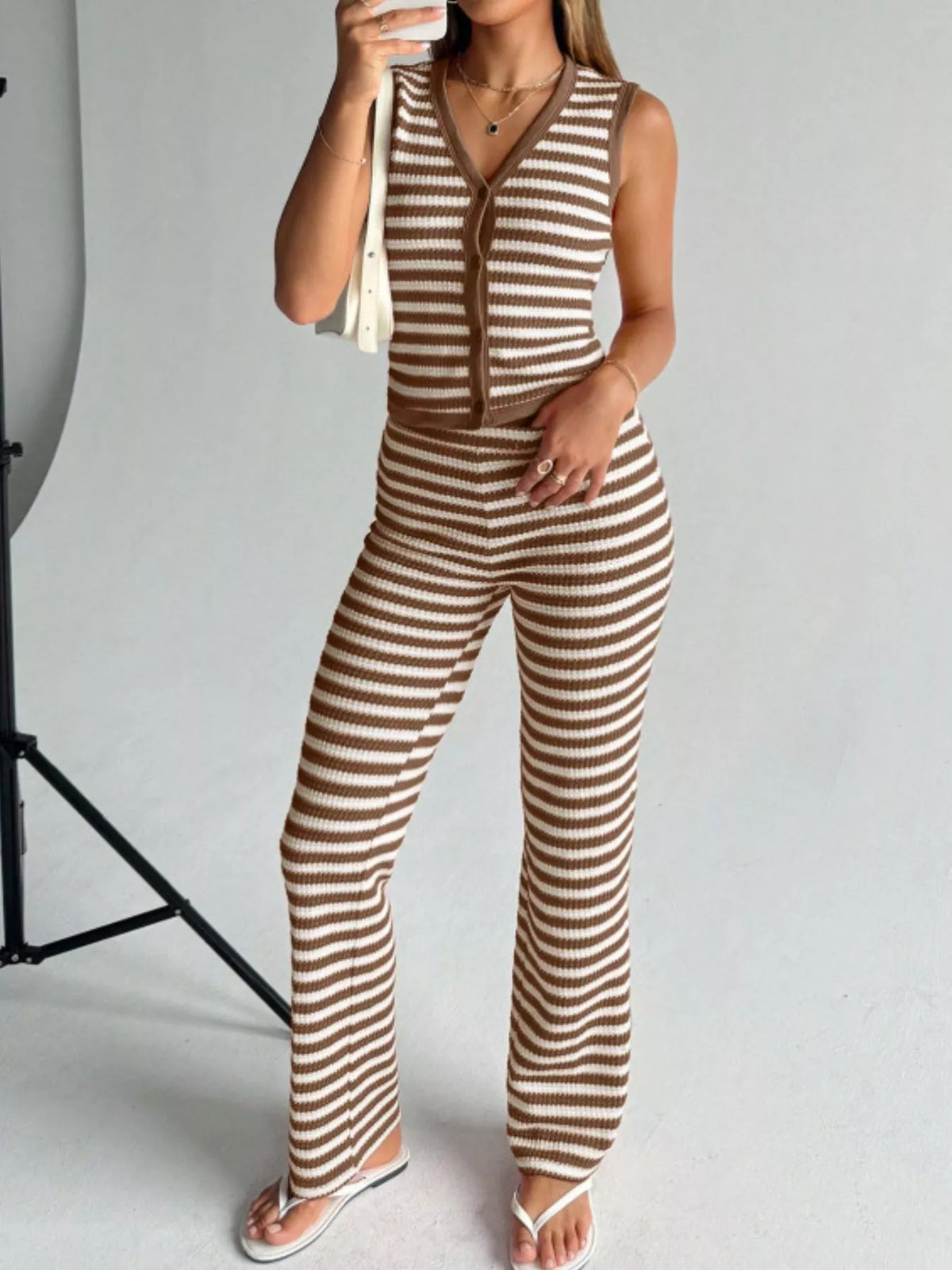 Striped knit V-neck sleeveless top and flare pants set by Plush Fashion Hub, featuring a stylish, casual outfit with a fitted top and flowing pants.