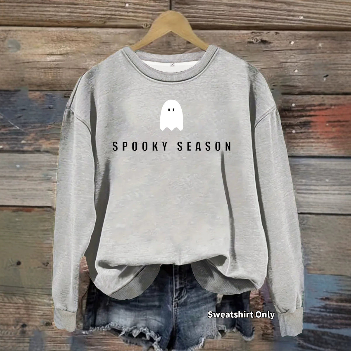 Light gray crewneck sweatshirt with "SPOOKY SEASON" and a white ghost printed on the chest, hanging on a hanger.