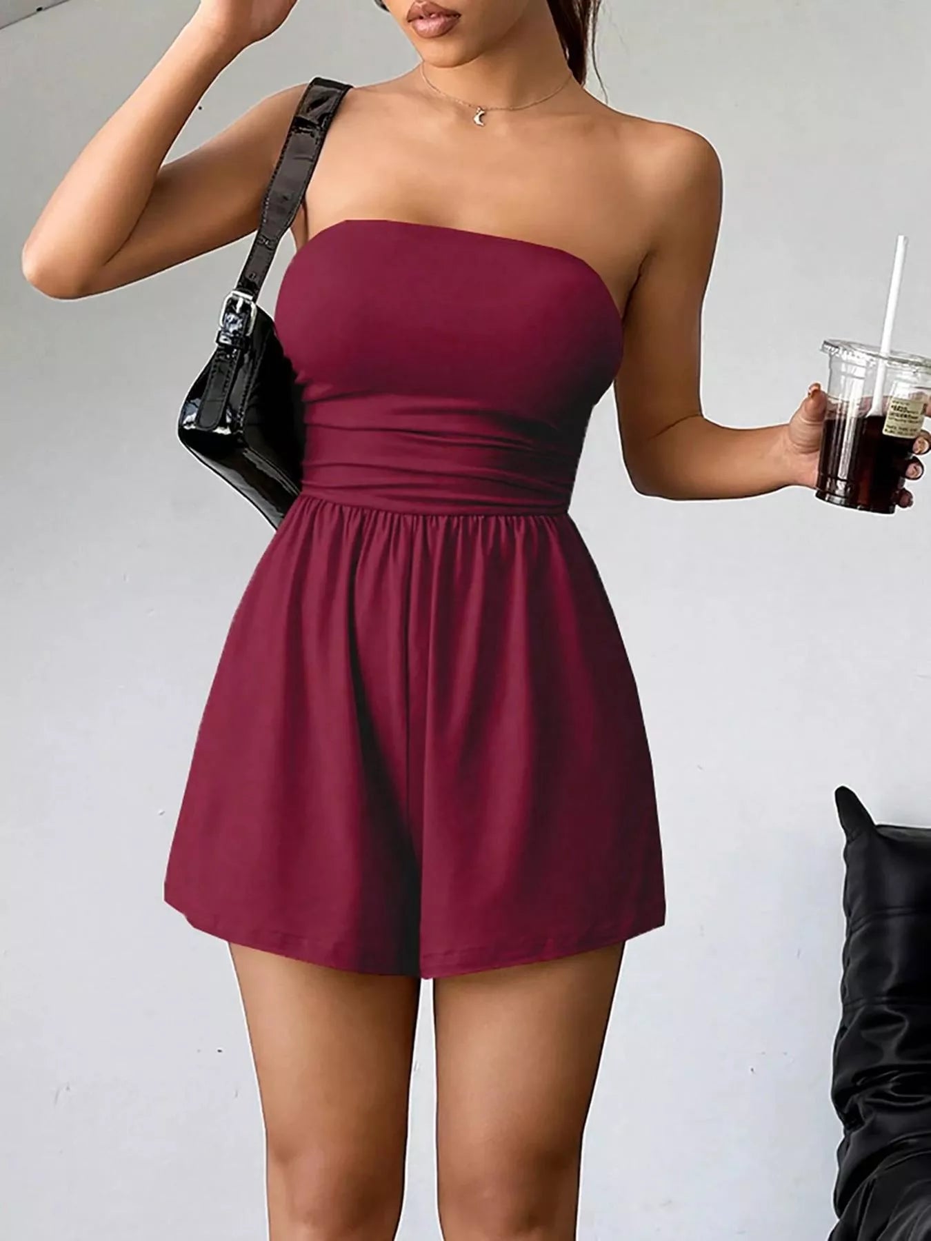 Black strapless romper with ruched waist and fitted design, perfect for stylish summer or casual occasions.
