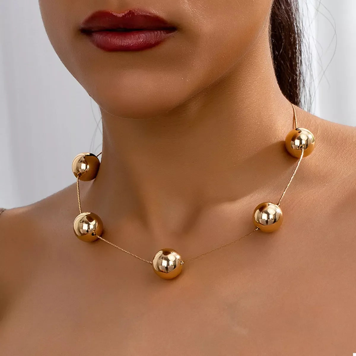 Golden Sphere Statement Necklace by Plush Fashion Hub featuring large, shiny gold orbs on a stylish chain.