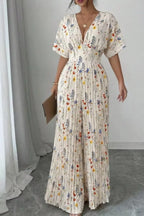 Floral print wide-leg pleated jumpsuit by Trendsi, featuring a stylish design with flowing fabric and adjustable straps.