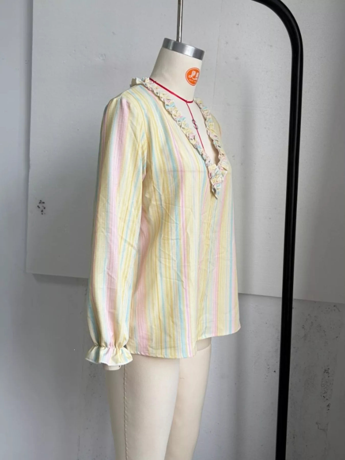 Striped ruffle-trim V-neck blouse from Trendsi, featuring a stylish design with ruffle details and a V-neck neckline.