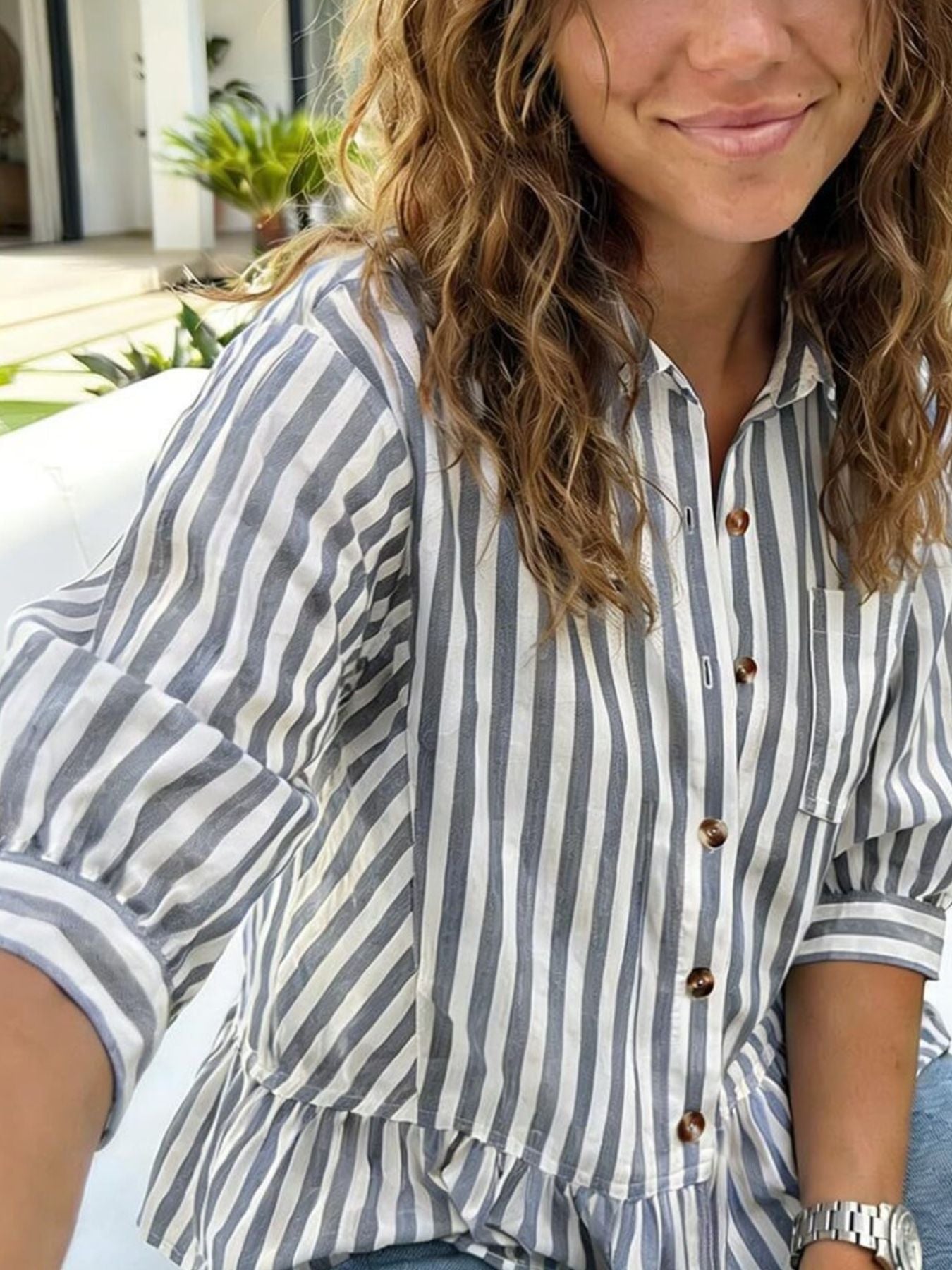 Women's striped button-down blouse with ruffled hem, lightweight viscose fabric, casual fit, styled with rolled-up sleeves.