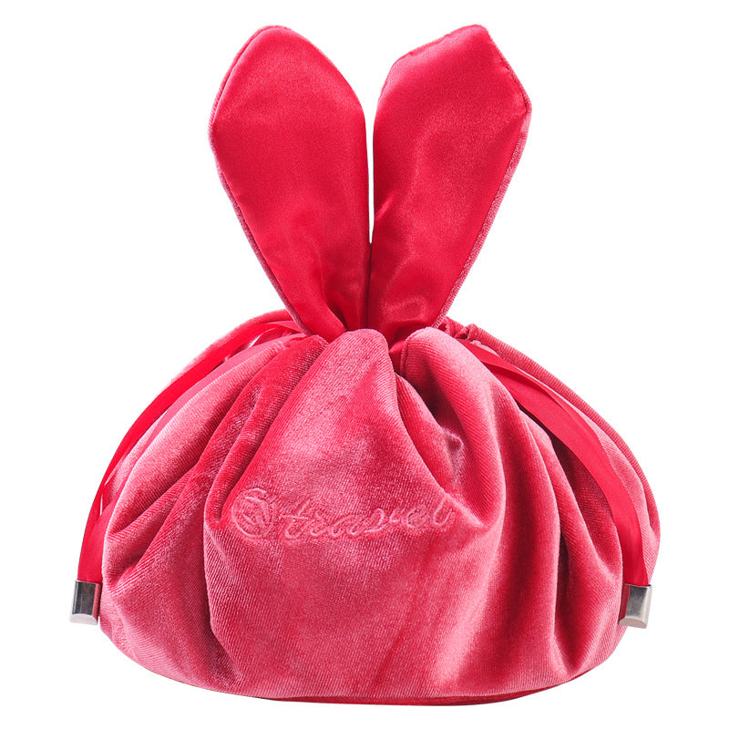 Red velvet drawstring pouch shaped like bunny ears with text, ribbons, and metal tips.