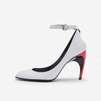 White pointed-toe leather stiletto with an ankle strap, buckle, and colorblock red and black sculptural heel.