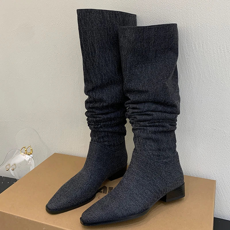 Dark grey slouchy knee-high boots with pointed toes and low block heels.